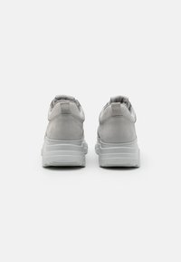 Baskets grises avec une finition texturée et un tissu doux au niveau du col, dotées d'une semelle blanche épaisse et d'un design minimaliste.