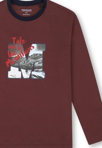 Bordeauxrotes Langarmshirt aus Bio-Baumwolle mit einem grafischen "M" und Berglandschaft sowie dem Text "Nimm mich zu den Bergen" in Rot.