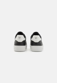 Sneaker nere in pelle con un tab del tallone bianco e logo argentato. Presentano un design testurizzato e suola in gomma. Stile semplice e moderno.