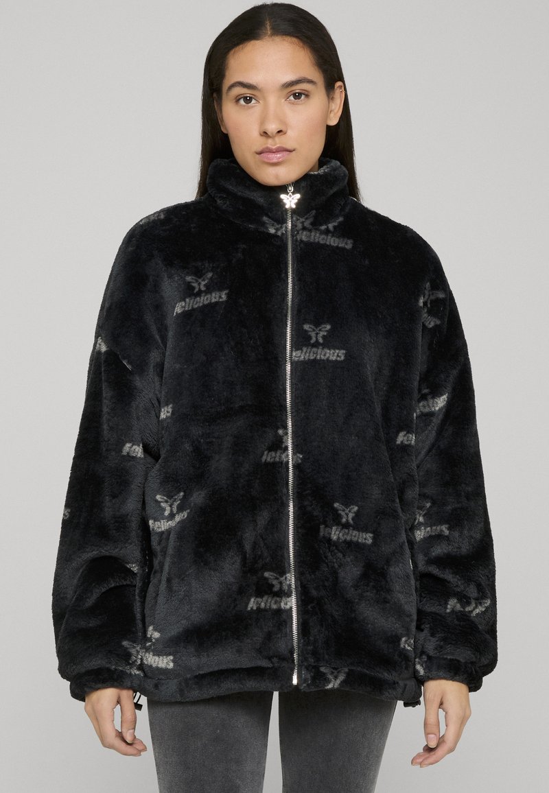 Fleecejakke med glidelås i svart med preget "Delicious"-mønster. Har høy krage og avslappet passform med vide ermer.