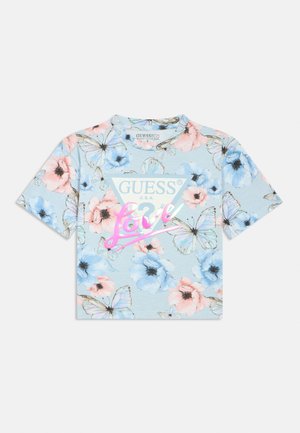 Kortermet blå bomulls-T-skjorte med blomstermønster i rosa og blå blomster, samt sommerfugldetaljer, med teksten "GUESS" og "Love" i rosa.