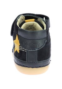 Zapato de ante negro para niños pequeños con detalle de estrella amarilla, correa de velcro ajustable, interior acolchado y suela de goma.