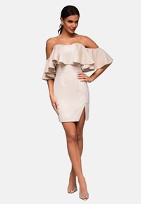 Robe beige décolletée avec un col en dentelle, silhouette ajustée et une fente jusqu'à la cuisse. Tissu texturé et design minimaliste.
