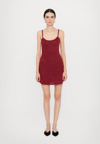 Rode glinsterende mini-jurk met dunne bandjes, aansluitende silhouette en een gladde textuur, gecombineerd met zwarte puntige ballerina's.