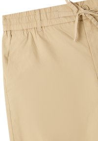 Pantaloni leggeri beige con vita elasticizzata, cordoncino regolabile e una texture liscia, dotati di tasche laterali e cuciture ordinate.