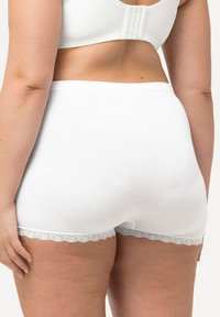 Vita bomullsshorts med spetsdetaljer vid fållen. Slät textur; enkel design med en bekväm, elastisk midja.