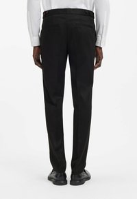 Pantaloni neri su misura con una texture liscia, due tasche posteriori e chiusura con bottone. Sono a taglio dritto e hanno un design classico.