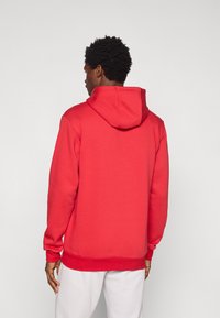 Κόκκινο φούτερ με κουκούλα και μακριά μανίκια, με μπροστινή τσέπη και ριμπ τελείωμα. Κατασκευασμένο από απαλό ύφασμα, παρουσιάζοντας άνετη εφαρμογή.