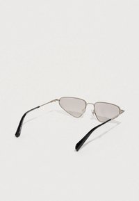 Óculos de sol com armação metálica em forma triangular, com lentes cinzentas e ponteiras de plástico pretas. Design minimalista, sem logótipos visíveis.