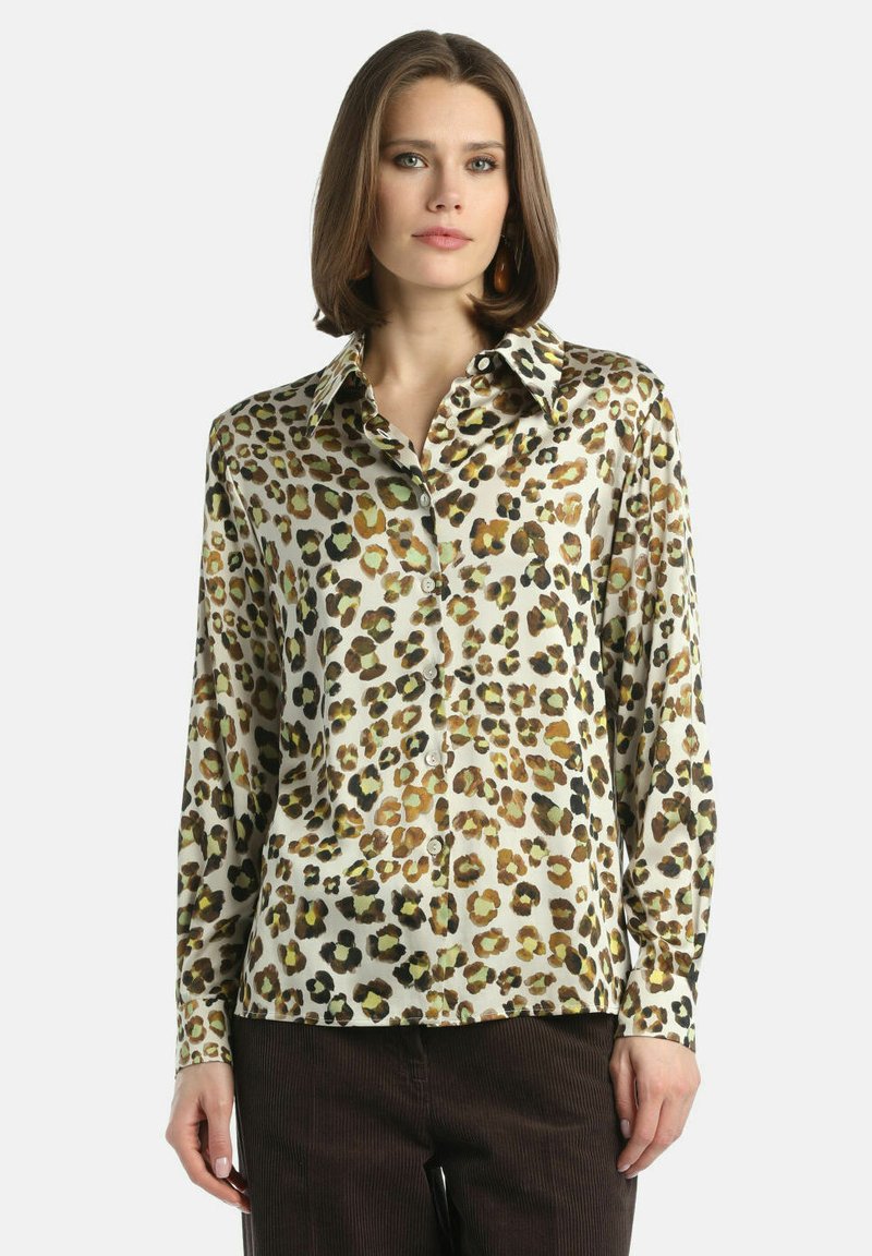 Blusa in stampa leopardata in morbido e setoso tessuto; presenta un colletto classico, chiusura con bottoni sul davanti e maniche lunghe con uno sfondo beige chiaro.