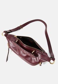 Sac à main en cuir bordeaux avec fermeture éclair, accents en métal doré et une bandoulière amovible. Détail de logo embossé à l'avant.