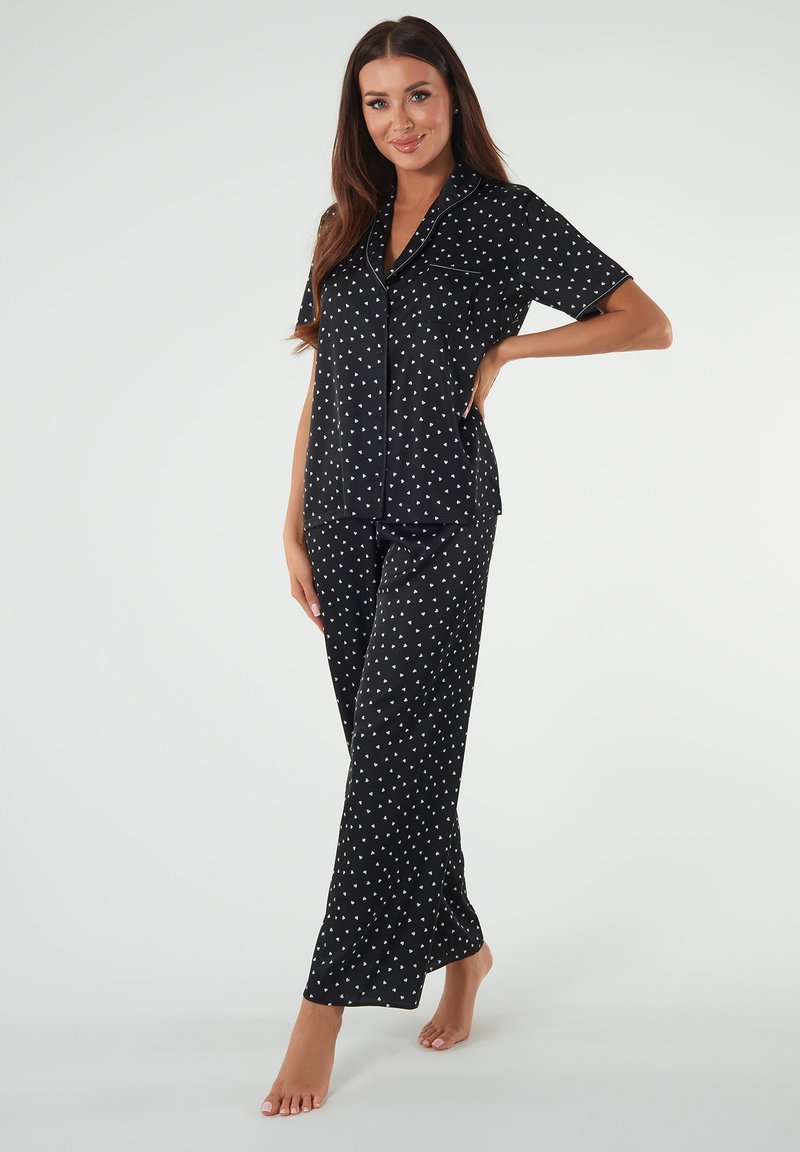 Czarny zestaw piżamowy z krótkimi rękawami, białym materiałem w serduszka, koszulą zapinaną na guziki oraz dopasowanymi spodniami prostymi.