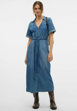 Dżinsowa sukienka z dekoltem w serek, krótkimi rękawami, zapinana na guziki z wiązanym wcięciem w talii. Średniej długości, z widocznymi szwami i luźnym krojem.