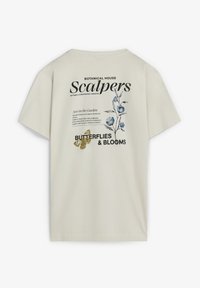 Camiseta de algodón color crema con gráficos florales, texto y acentos de mariposa en la parte posterior; diseño casual de manga corta.