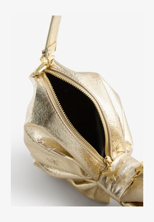 Sac à main métallique doré avec un extérieur texturé, fermeture éclair et intérieur noir. Comprend un charm étoile décoratif sur la fermeture éclair.