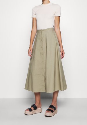 Woman wearing a short-sleeve white ribbed top, high-waisted button-front olive green midi skirt, and black platform sandals.