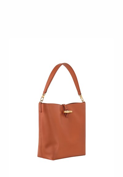 Braune Leder-Schultertasche mit strukturierter Form, kurzem Griff und goldenen Hardware-Details am Verschluss. Glatte Textur mit minimalen Akzenten.