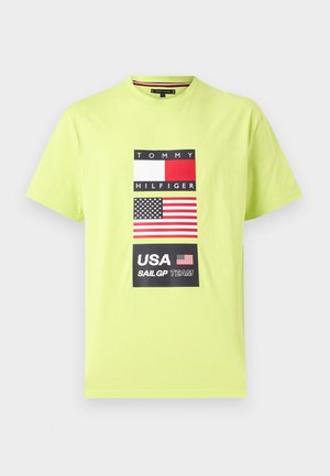 Svetlozelené tričko s okrúhlym výstrihom s logom Tommy Hilfiger, americkou vlajkou a textom „USA SailGP Team“ na prednej strane.
