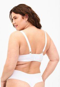 White bra with adjustable straps and hook-and-eye closure. Smooth fabric with minimal visible seams. Plain design, no patterns or embellishments.