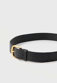 Juodas odinis diržas su faktūruota apdaila. Turi auksinę metalinę sagtį ir lygią vidinę pamušalą. Minimalistinis dizainas ir klasikinė forma.