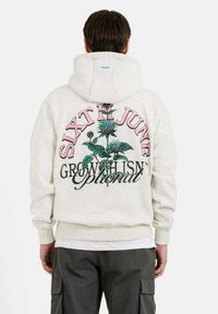 Lichtgrijze hoodie met een bloemig grafisch ontwerp op de achterkant, met de teksten "SIXTH JUNE" en "GROEI IS GEEN OPTIE." Gemaakt van een katoenmix.