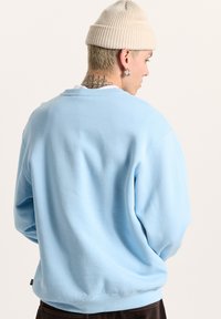Felpa a girocollo di cotone azzurro chiaro con una vestibilità comoda. Presenta polsini e orlo a coste, con una texture morbida e liscia.