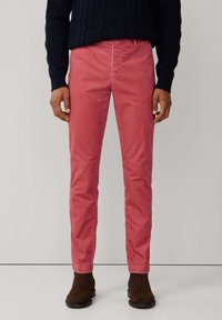 Rode katoenen chino broek met een slim fit en subtiele textuur, met zijzakken en een taps toelopend model, gedragen met donkerbruine enkelboots.