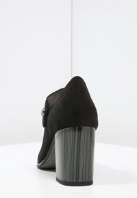 Czarne zamszowe szpilki z ostrym noskiem i teksturowanym szarym słupkiem. Zawierają detal w postaci guzika po boku.