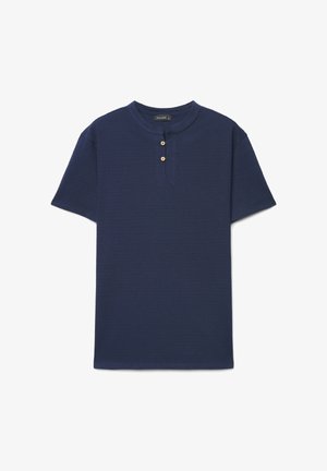 Marineblaue Henley-Tunika mit kurzen Ärmeln, zwei Holzknöpfen und rundem Ausschnitt vor weißem Hintergrund.