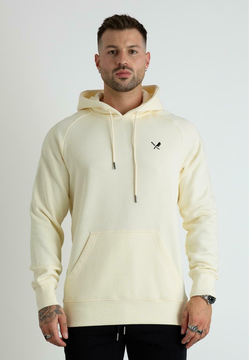 Felpa con cappuccio color crema, dotata di tasca a marsupio e un logo nero in accentuazione sul petto. Il tessuto sembra morbido con polsini a coste.