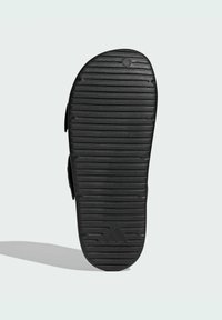 Sort slide sandal med tekstureret gummisål, der har horisontale riller og et hævet logo. Glat materiale og åbent design for åndbarhed.