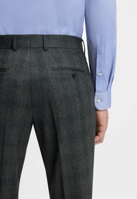 Donkergrijze geblokte broek met verticale blauwe strepen, slim fit, riemlussen en twee achterzakken, gecombineerd met een lichtblauw overhemd.