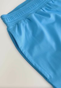 Shorts sportive albastre dintr-un material texturat, cu talie elastică și buzunare laterale. Suprafață netedă cu un model geometric.