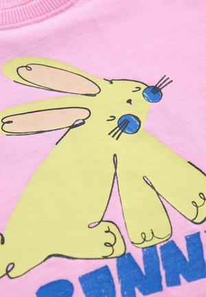 Tela rosa con un conejo amarillo de estilo de dibujos animados, ojos azules y orejas largas. El texto debajo, en letras azules en negrita, dice "BUNNY".