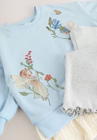 Jasnoniebieska bluza z haftem kwiatów i wróżek o miękkich fakturach. W zestawie z jasnoszarą dzianiną prążkowaną z falbankami.