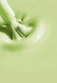 Una vernice verde chiaro con una consistenza liscia e lucida si avvolge attorno a un pennello, che ha setole morbide e un manico lucido.