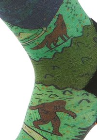Calzini verdi con motivi a tema forestale, tra cui un lupo marrone e un Bigfoot marrone, con una finitura testurizzata e un polsino nero a contrasto.