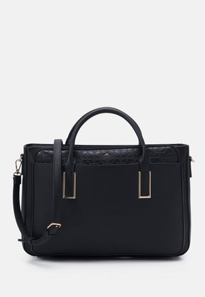 Sac à main en cuir noir avec partie supérieure texturée, ferrures dorées, deux poignées et une bandoulière réglable sur fond uni.