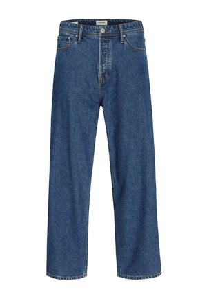 Dreng smilende iført en blå og hvid langærmet skjorte, brede blå jeans, beige sko og en blå kasket mod en hvid baggrund.