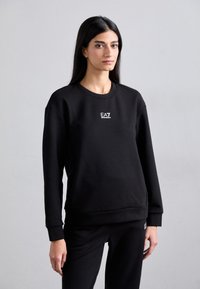 Felpa nera realizzata in morbido misto cotone, con scollo rotondo, polsini a costine e un piccolo logo EA7 bianco sul petto.