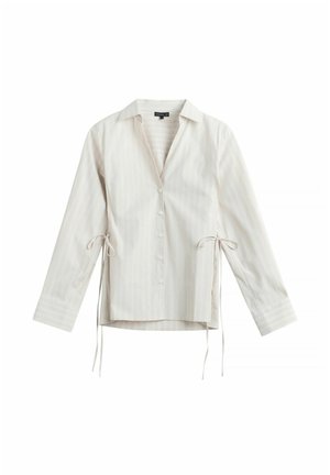 Pitkähihainen valkoinen nappikauluspaita, jossa on ohuet pystysuorat raidat ja sivusolmimiset, kaulus ja kalvosimet, esitetty valkoisella taustalla.