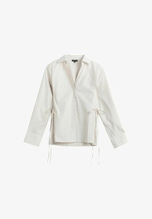 Pitkähihainen valkoinen nappikauluspaita, jossa on ohuet pystysuorat raidat ja sivusolmimiset, kaulus ja kalvosimet, esitetty valkoisella taustalla.