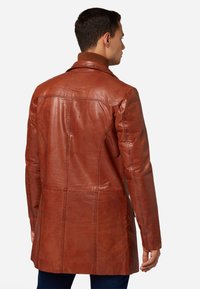 Bruine leren jas met een gladde textuur, elegante pasvorm en middelmatige lengte. Heeft een verhoogde kraag en verticale naden.
