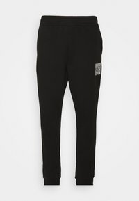 Svarta sweatpants med elastisk midja, avsmalnande ben och en liten strukturerad logotyp på vänster lår. Material av bomullsblandning.