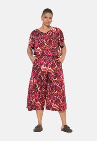 Felkleurige two-piece outfit met een losse top en broek met wijde pijpen in roze, rood, oranje en zwarte tinten. Zachte stofstructuur.