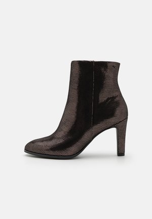Bottine noire avec un bout pointu et un design texturé. Dotée d'une finition lisse et brillante ainsi que d'un talon haut mince. Silhouette simple et épurée.