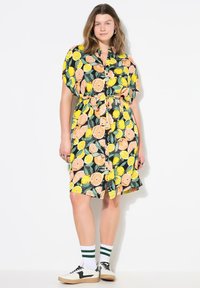Abito camicia con stampa agrumata di arance e limoni su sfondo nero. Realizzato in tessuto leggero con vita arricciata.