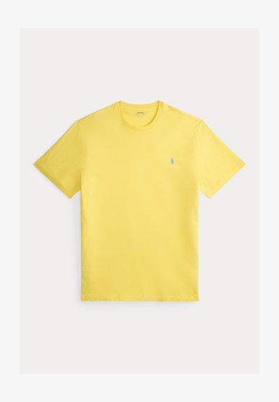 Žuta pamučna majica s okruglim izrezom, kratkim rukavima i malim plavim logotipom na lijevoj strani prsa. Glatka tekstura, redoviti kroj.