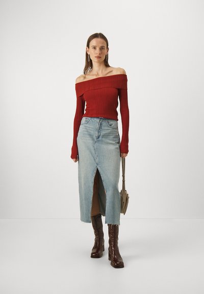 Red ribbed off-shoulder top, light blue denim skirt with front slit, worn with knee-high dark brown leather boots. Casual outfit.