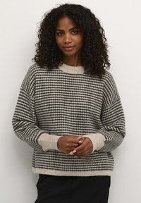 Pull rayé gris et crème en tricot doux, avec un col rond et des poignets côtelés, un ajustement ample et une surface texturée.